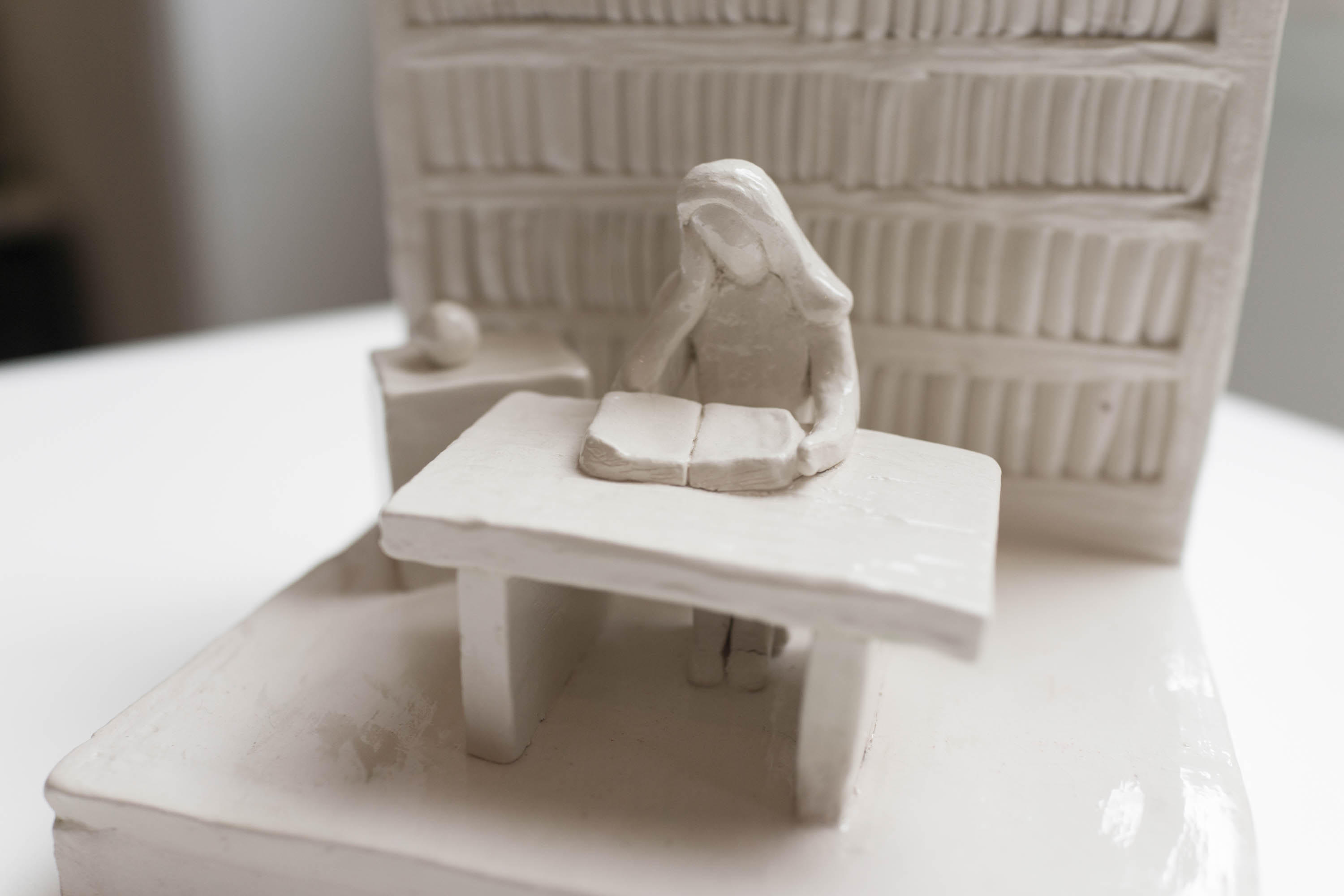 Clay model of a woman sitting at a desk